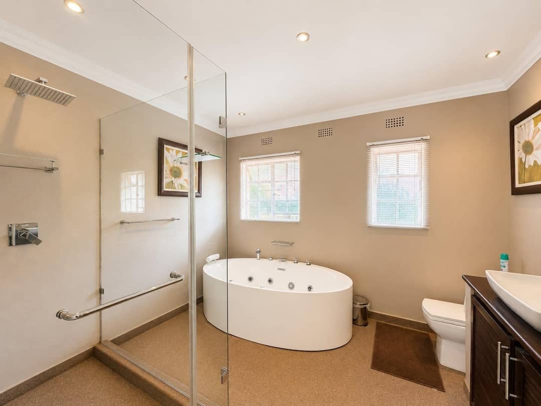 Main bathroom with an oval jacuzzi tub and a large walk-in rain shower behind glass