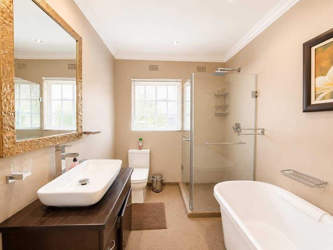 Bathroom with a freestanding oval tub, walk-in glass shower and a vessel basin on a dark timber vanity