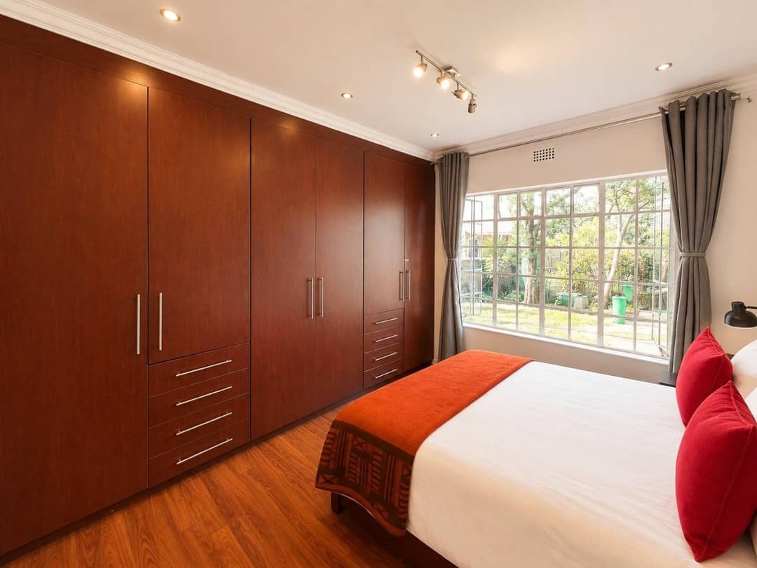 Main bedroom with a full wall of mahogany built-in cupboards and a garden-facing window