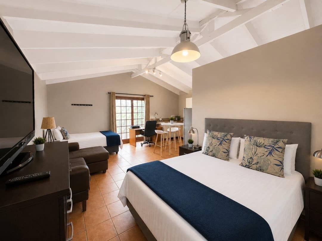 Upstairs studio from the other end, showing the bed, sofa, TV and kitchenette beyond