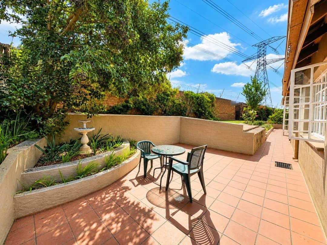 Paved courtyard with tiered planters, a small fountain and a bistro table shaded by a leafy tree