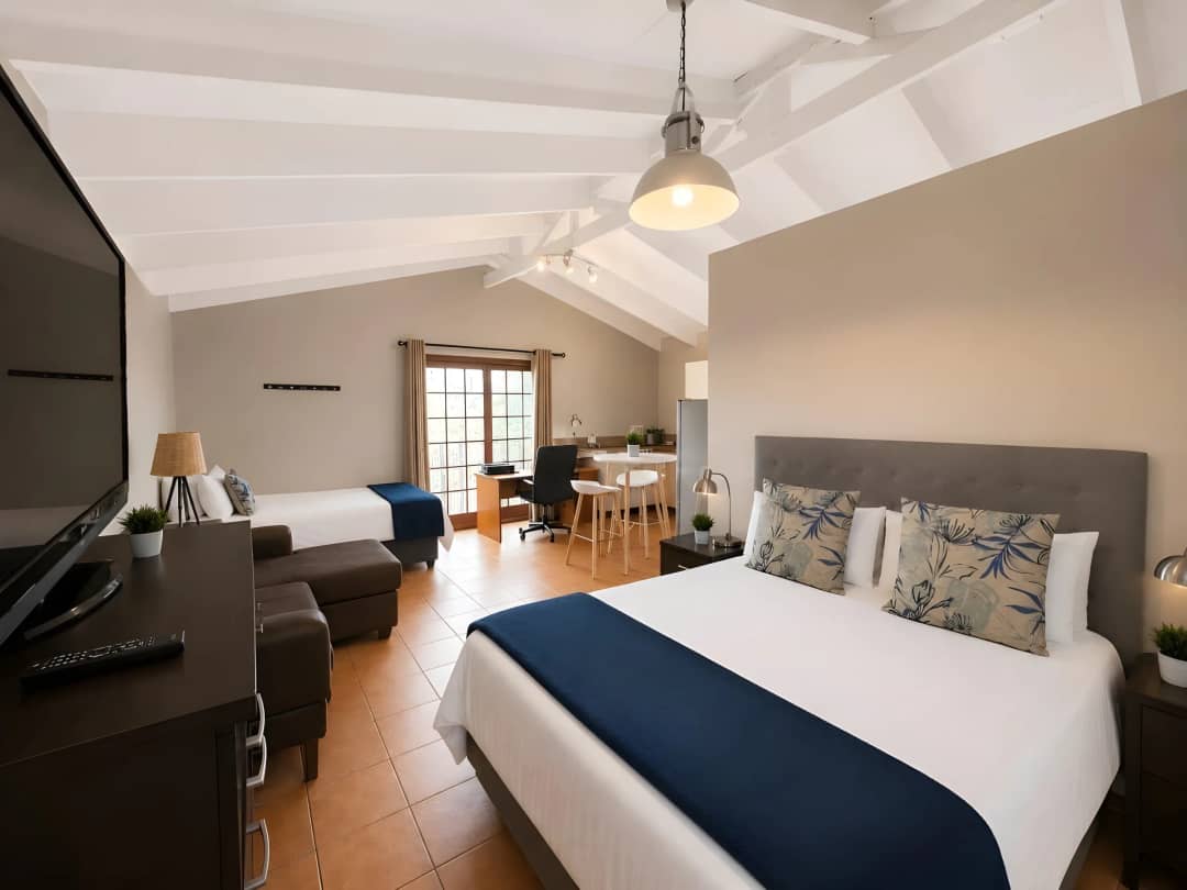 Upstairs studio from the other end, showing the bed, sofa, TV and kitchenette beyond
