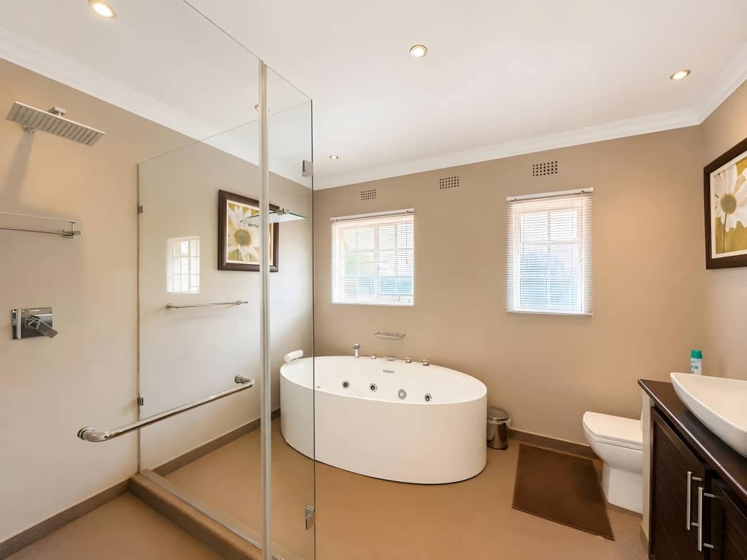 Main bathroom with an oval jacuzzi tub and a large walk-in rain shower behind glass