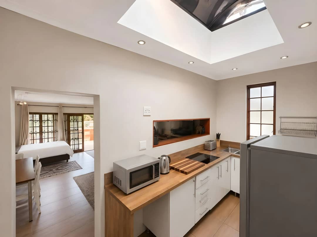 Self-catering kitchenette with a skylight, induction hob, microwave and fridge, opening to a bedroom